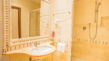 A bathroom with a sink, mirror, and shower.