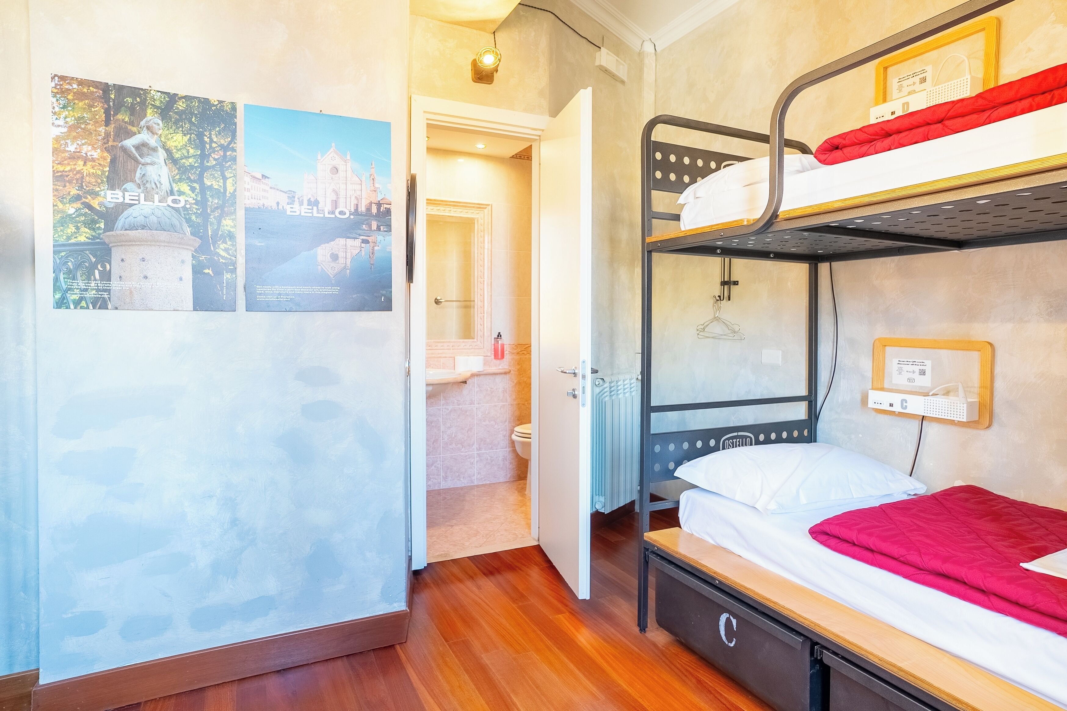 A bunk bed room with a wooden floor, a radiator, a hanging light fixture, and a framed picture on the wall.