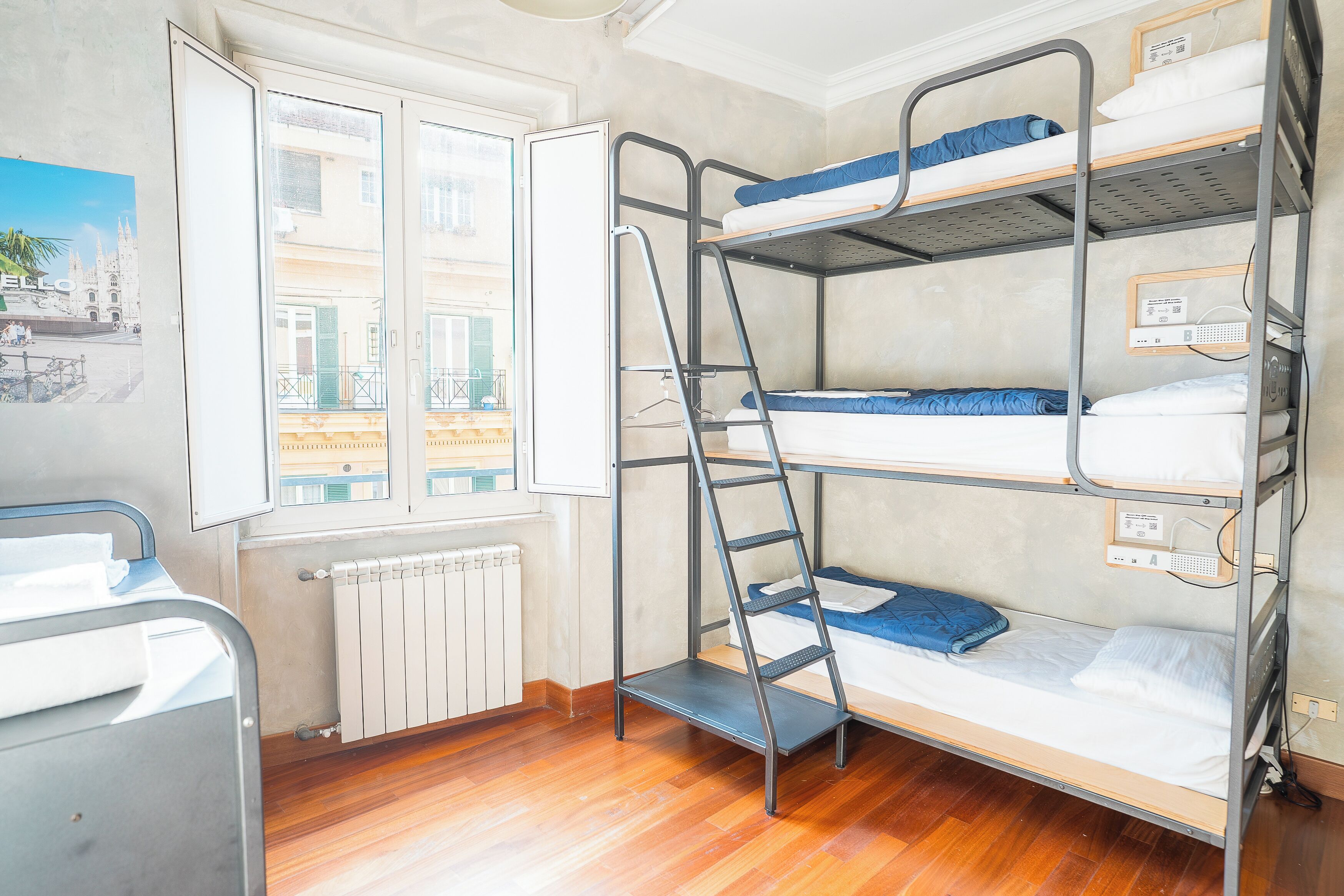 A bunk bed room with a window, radiator, and a bed with a pillow.