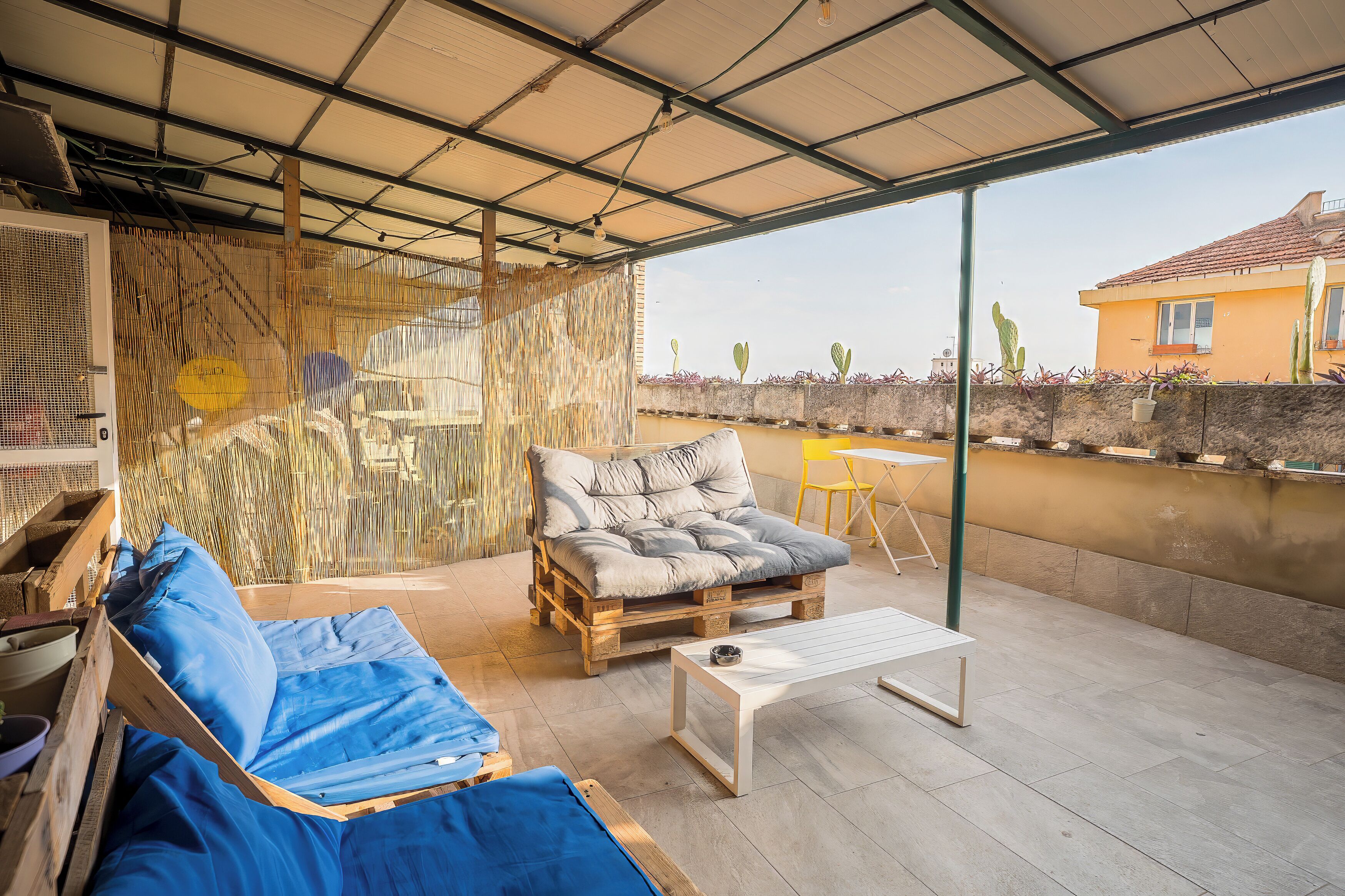A covered patio with a sofa, a coffee table, and a chair.