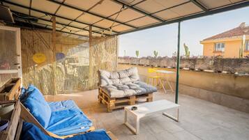 A covered patio with a sofa, a coffee table, and a chair.