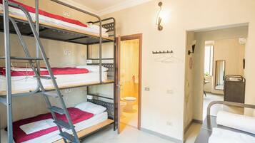 Een slaapkamer met een stapelbed, een houten deur naar een badkamer en een kapstok met hangers.