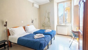 Una habitación de hotel con dos camas, una ventana con vistas, un radiador y una silla.