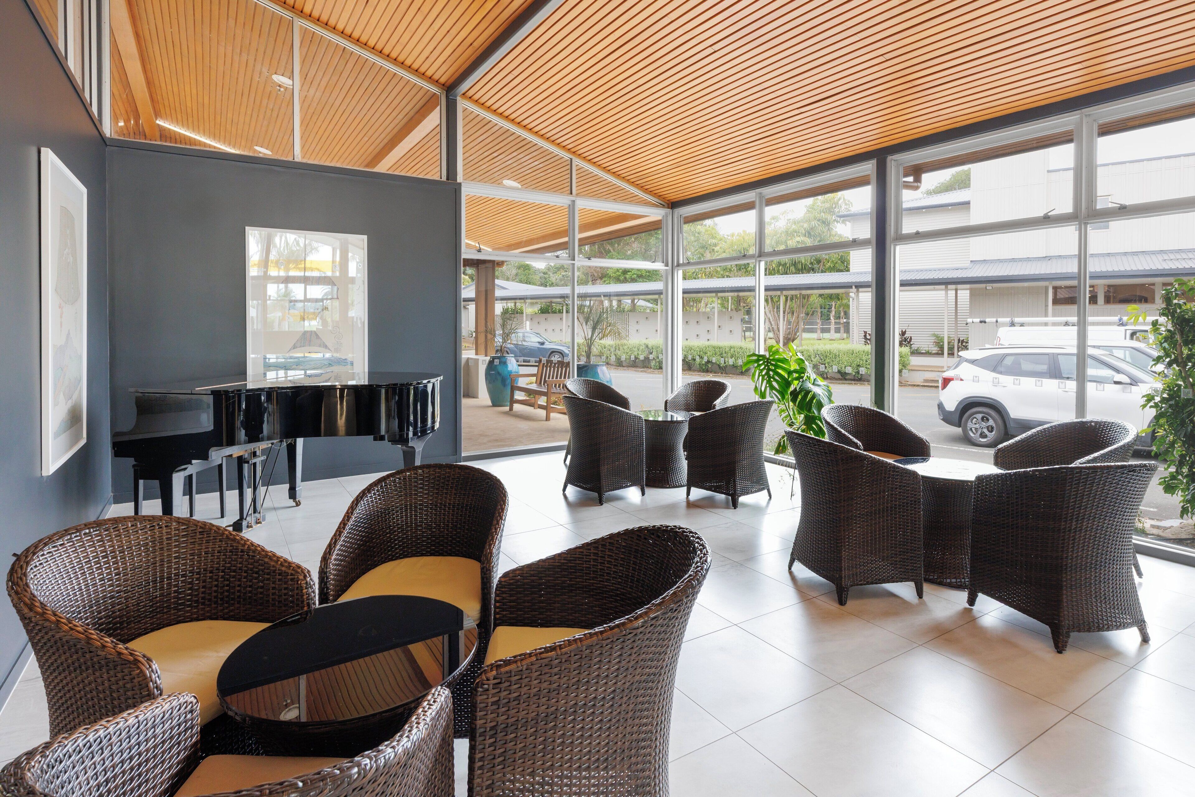 A modern indoor seating area with wicker furniture and a large window overlooking a parking area.