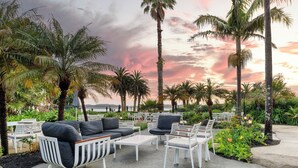An outdoor seating area with white furniture and palm trees, set against a sunset sky. - Copthorne Hotel and Resort Bay of Islands (Waitangi)