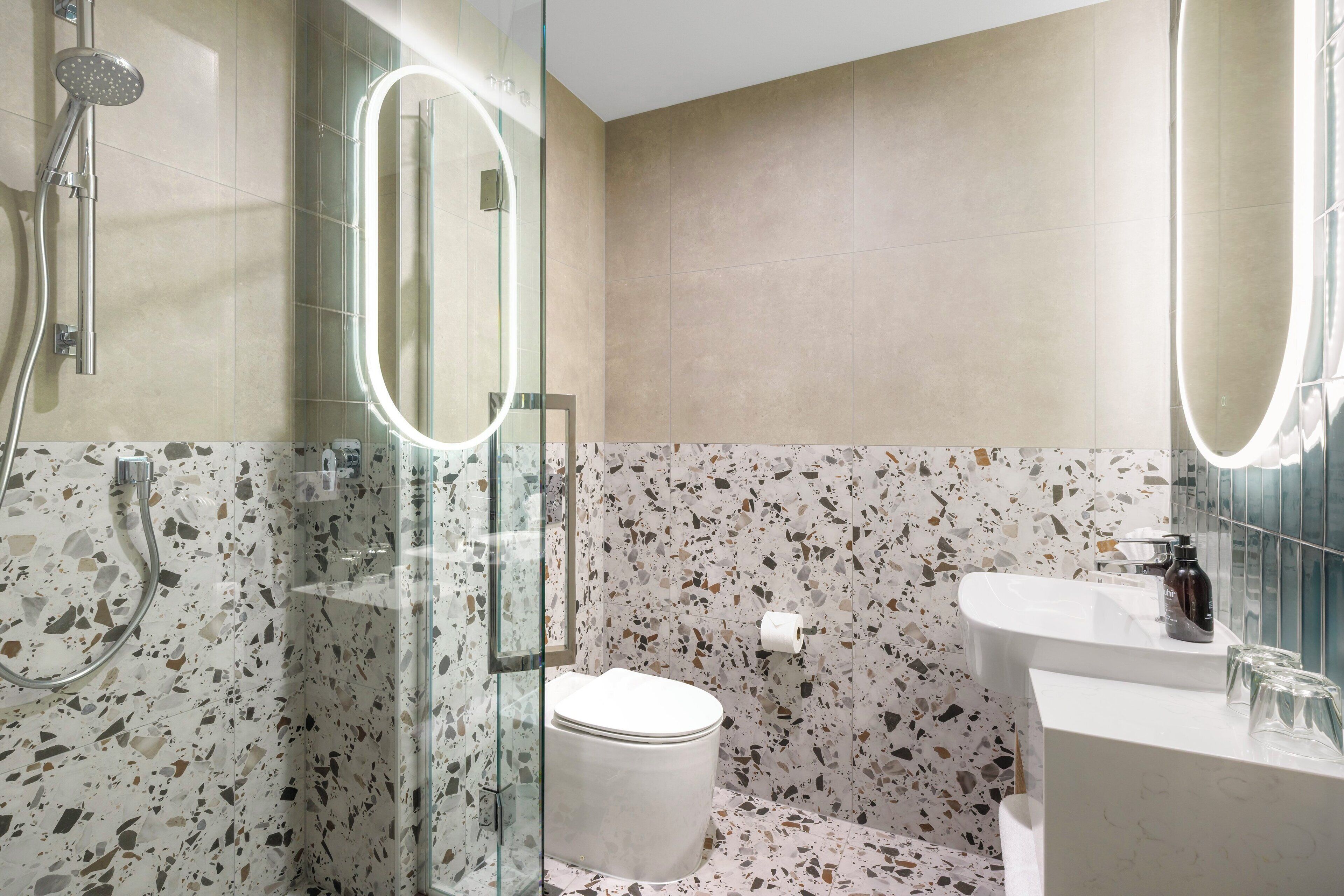 Une salle de bain moderne avec une douche à parois de verre, des toilettes et un lavabo avec un miroir.