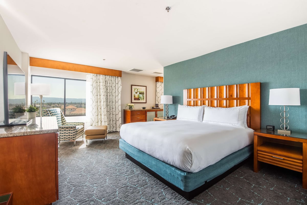 Ein Hotelzimmer mit einem großen Bett, einem Schreibtisch, einem Stuhl und Blick auf die Stadt.