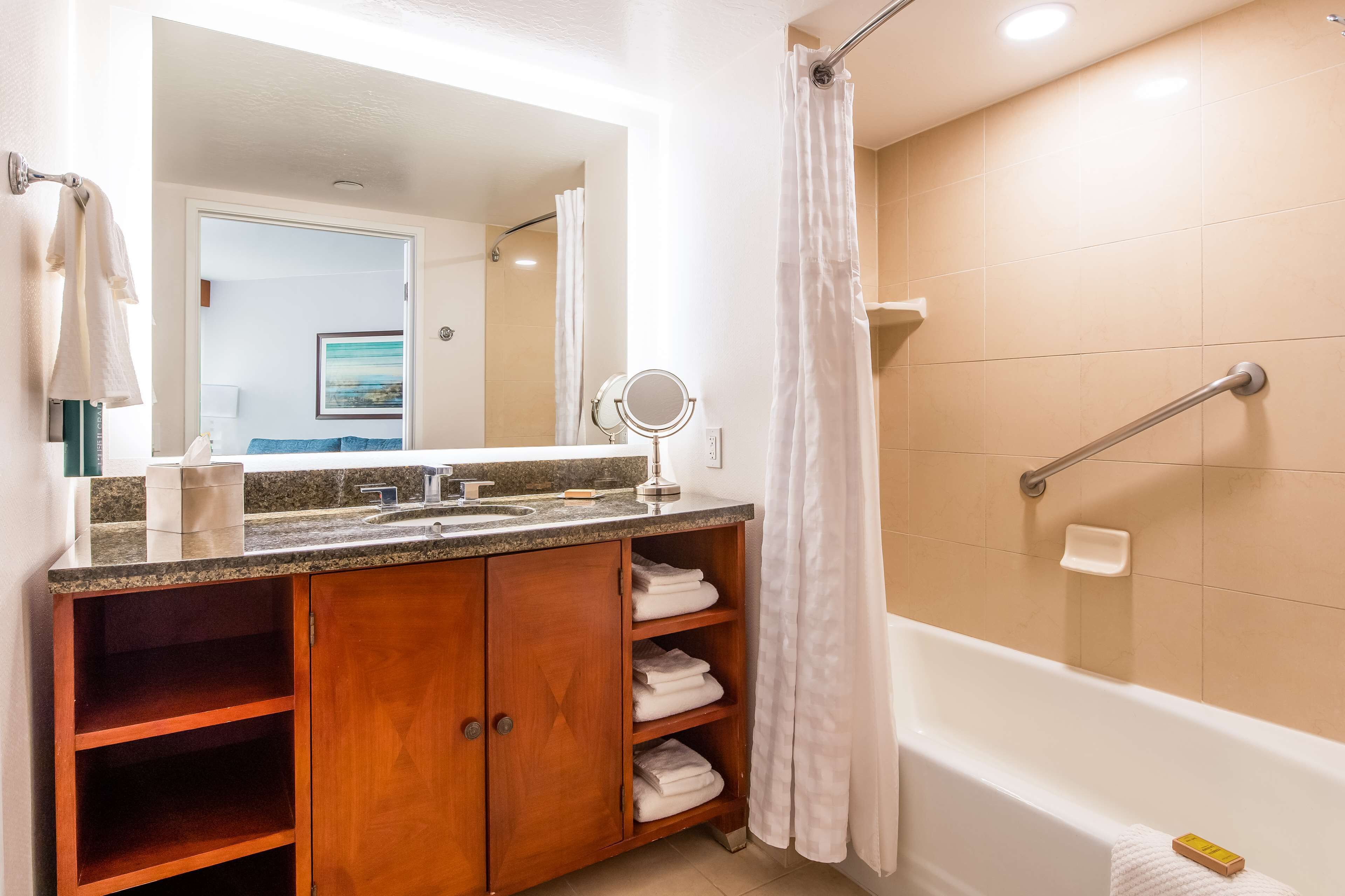 A bathroom with a wooden vanity, a bathtub, and a shower curtain.
