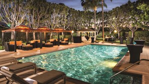 A pool area with lounge chairs, a gazebo, and a small pavilion surrounded by trees. - DoubleTree by Hilton Carson (Carson)