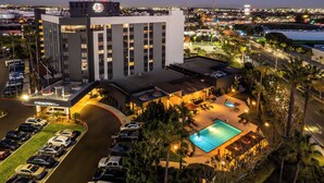 A hotel with a swimming pool, parking lot, and a view of the city at dusk. - DoubleTree by Hilton Carson (Carson)