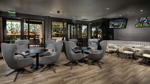 A modern lounge area with grey upholstered chairs, round tables, and a white sofa. - DoubleTree by Hilton Carson (Carson)