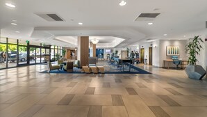 A spacious lobby with a modern design, featuring a central seating area, a reception desk, and a large window offering a view of the street. - DoubleTree by Hilton Carson (Carson)