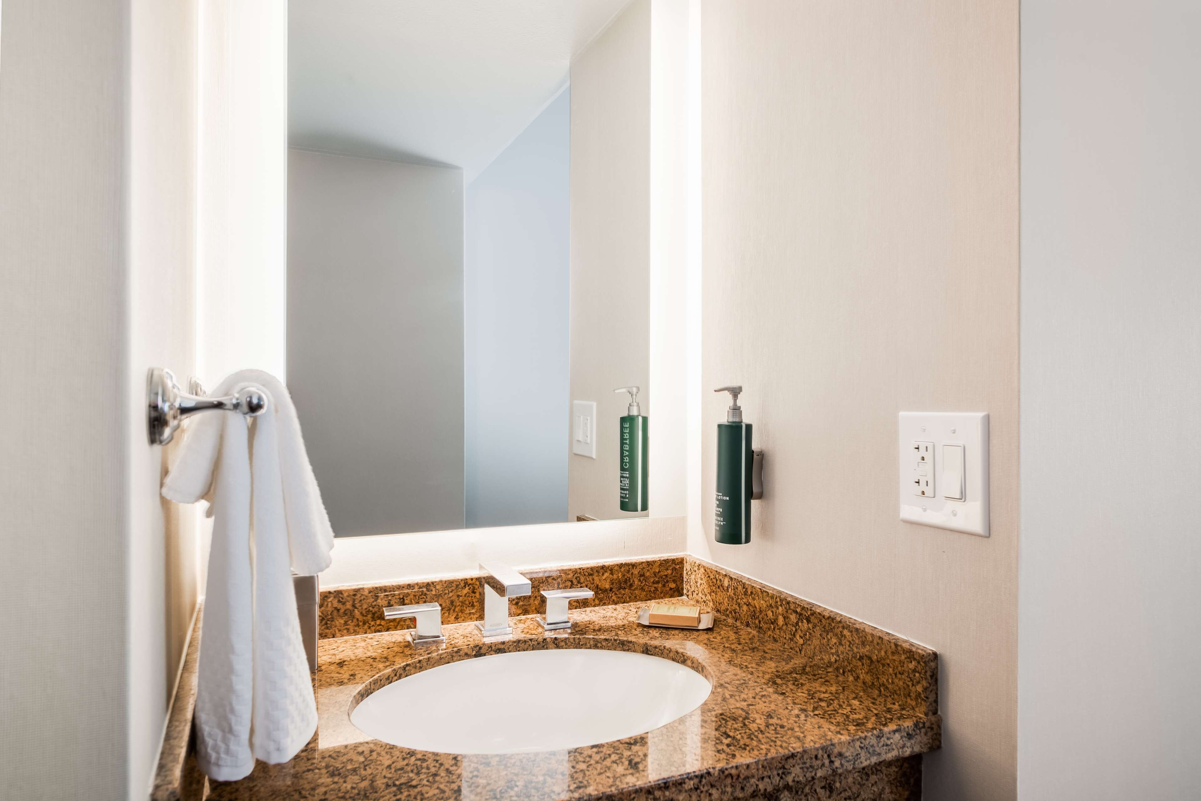 A bathroom with a granite countertop, a white sink, and a towel rack.