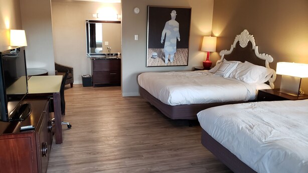 A hotel room with two beds, a desk, a chair, a dresser, and a bathroom visible through an open door. - Yakima Valley Inn (Yakima)