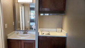 A bathroom with a white sink, a mirror, and wooden cabinets. - Yakima Valley Inn (Yakima)