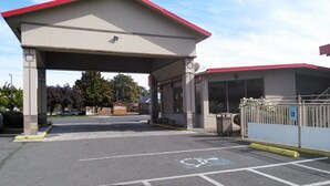 A parking area with designated handicapped spaces and a covered entrance to a building. - Yakima Valley Inn (Yakima)