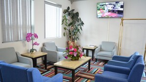 A room with a sofa, chairs, a coffee table, a TV, and a plant. - Days Inn by Wyndham Syracuse (Syracuse)