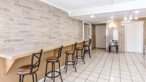 A reception area with a brick wall, a counter, and four bar stools. - Days Inn by Wyndham Syracuse (Syracuse)