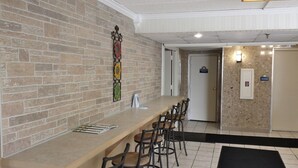 A reception area with a brick wall, a reception desk, and a few chairs. - Days Inn by Wyndham Syracuse (Syracuse)