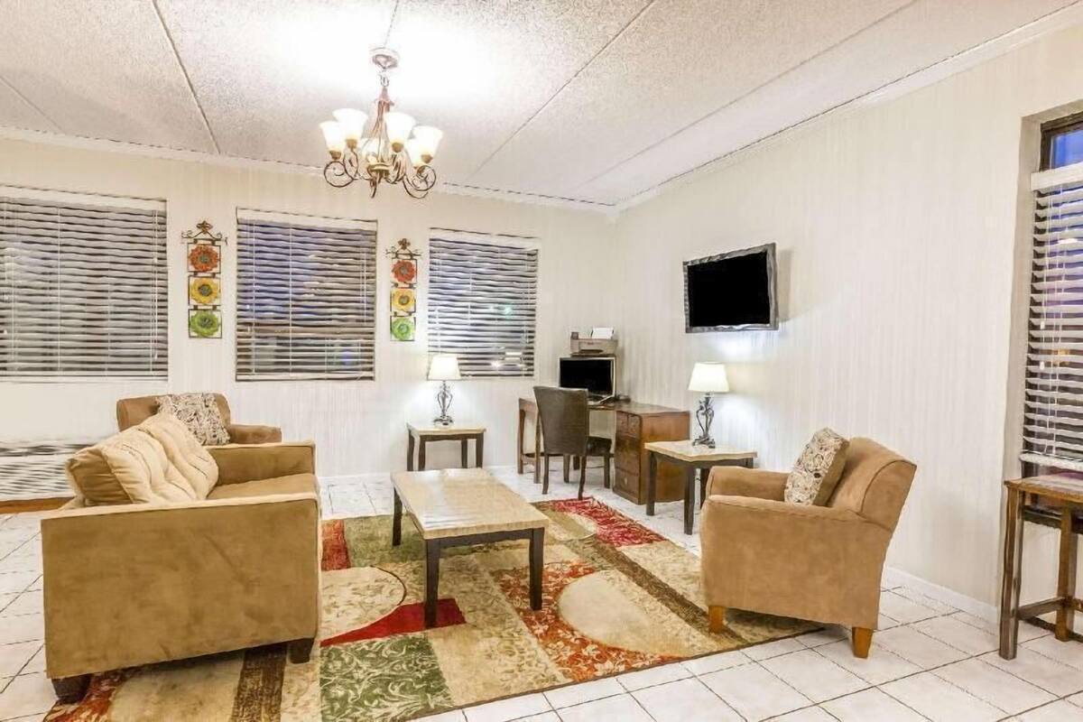 A living room with a sofa, armchairs, a coffee table, a TV, and a chandelier.