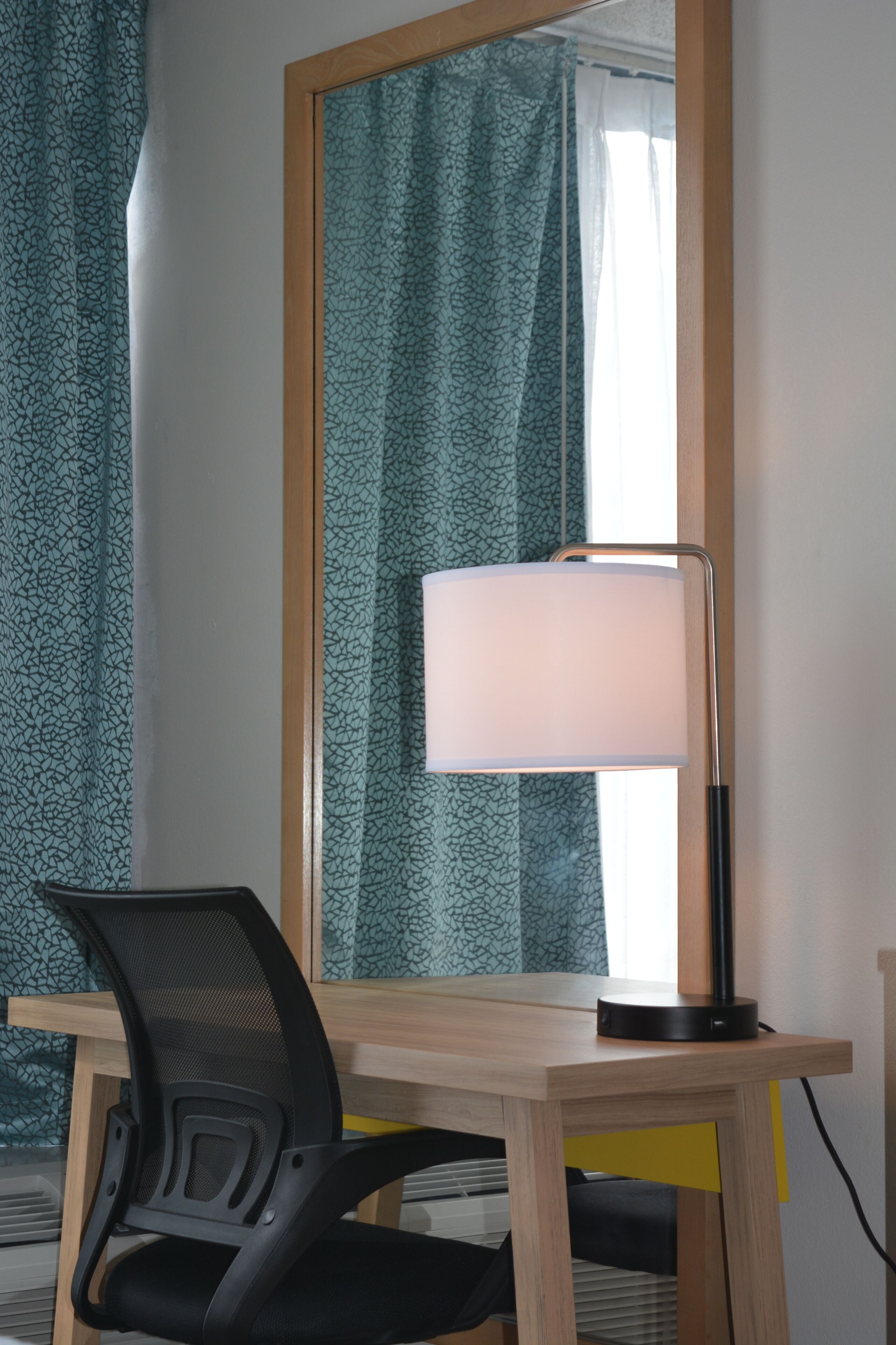 A desk with a lamp, a chair, and a mirror.