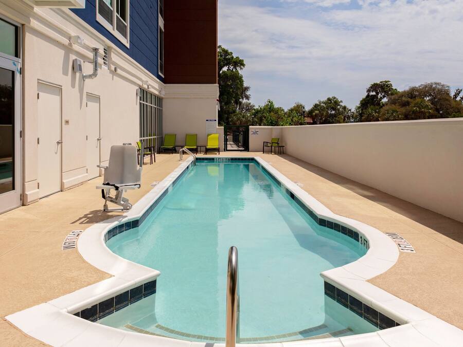 A swimming pool with a curved edge, a metal handrail, and a tiled deck.