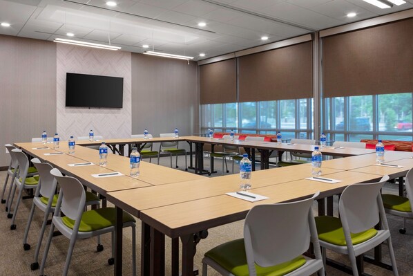 Un salón de conferencias con varias mesas, sillas y botellas de agua.