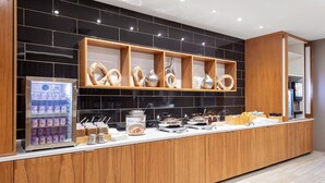 A modern breakfast bar with a refrigerated drink dispenser, a variety of breakfast items, and decorative wooden shelves. - SpringHill Suites by Marriott Beaufort (Beaufort)