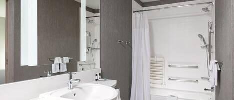 Un baño moderno con tocador doble, un espejo grande, una bañera con ducha y un perchero para toallas.