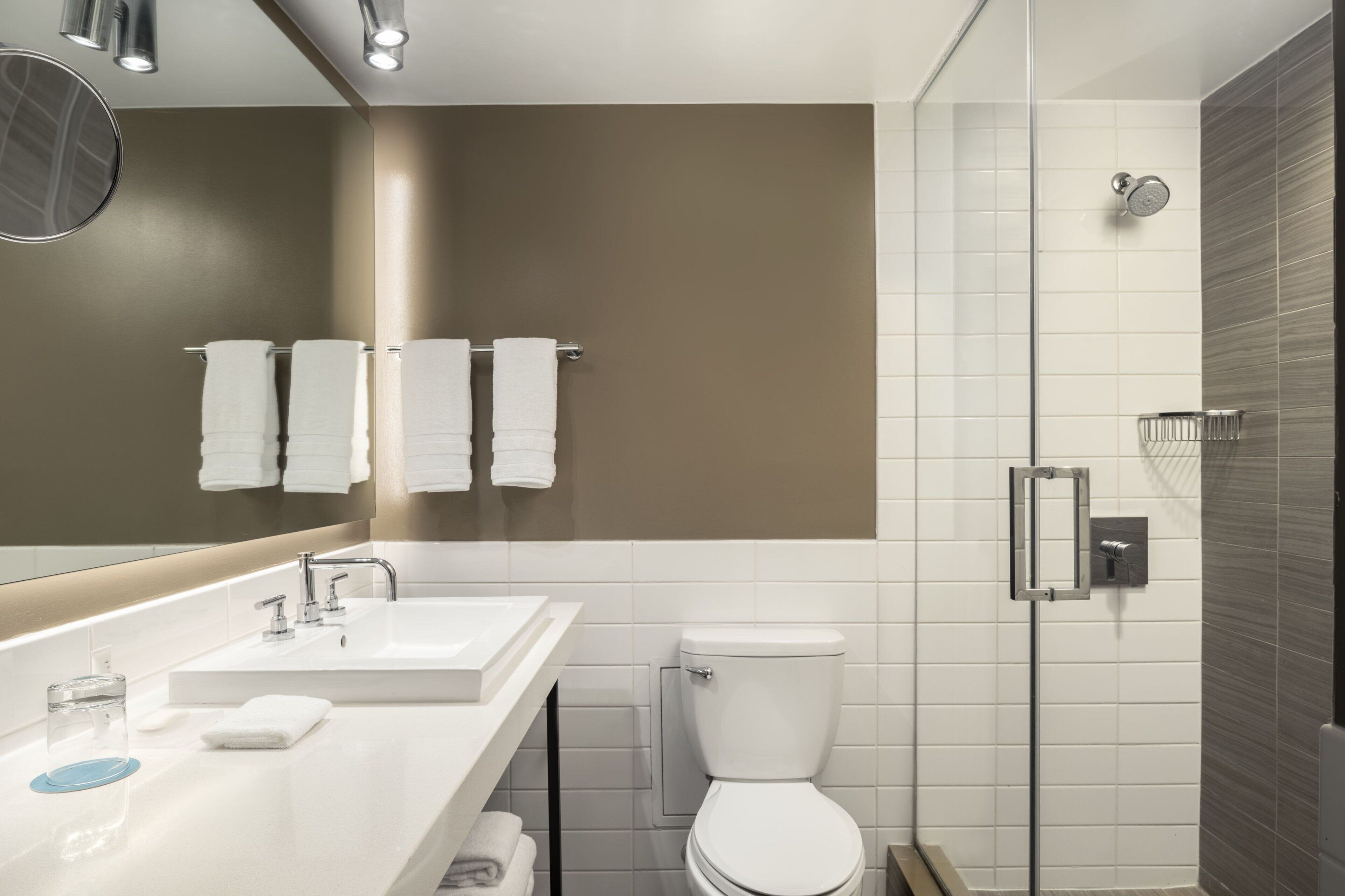 Een moderne badkamer met een wit wastafelmeubel, een spiegel, een toilet en een douche.