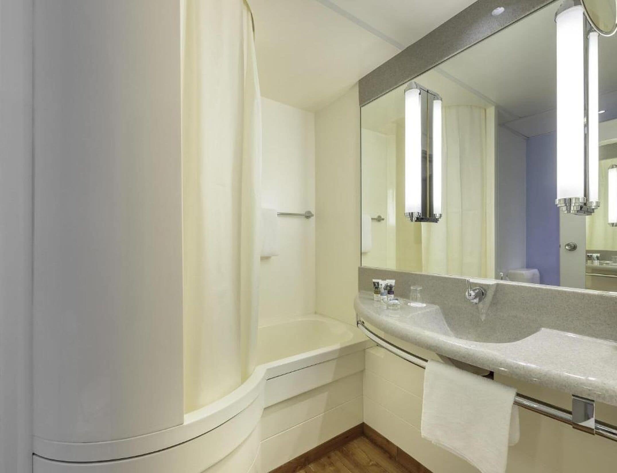 Une salle de bain moderne avec une douche, un lavabo et un grand miroir.