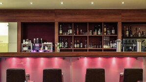 Una zona de bar con estantes llenos de botellas de licores, una máquina de café y asientos con mesas y sillas.