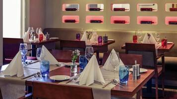A restaurant interior with tables set for dining, glasses, and cutlery.