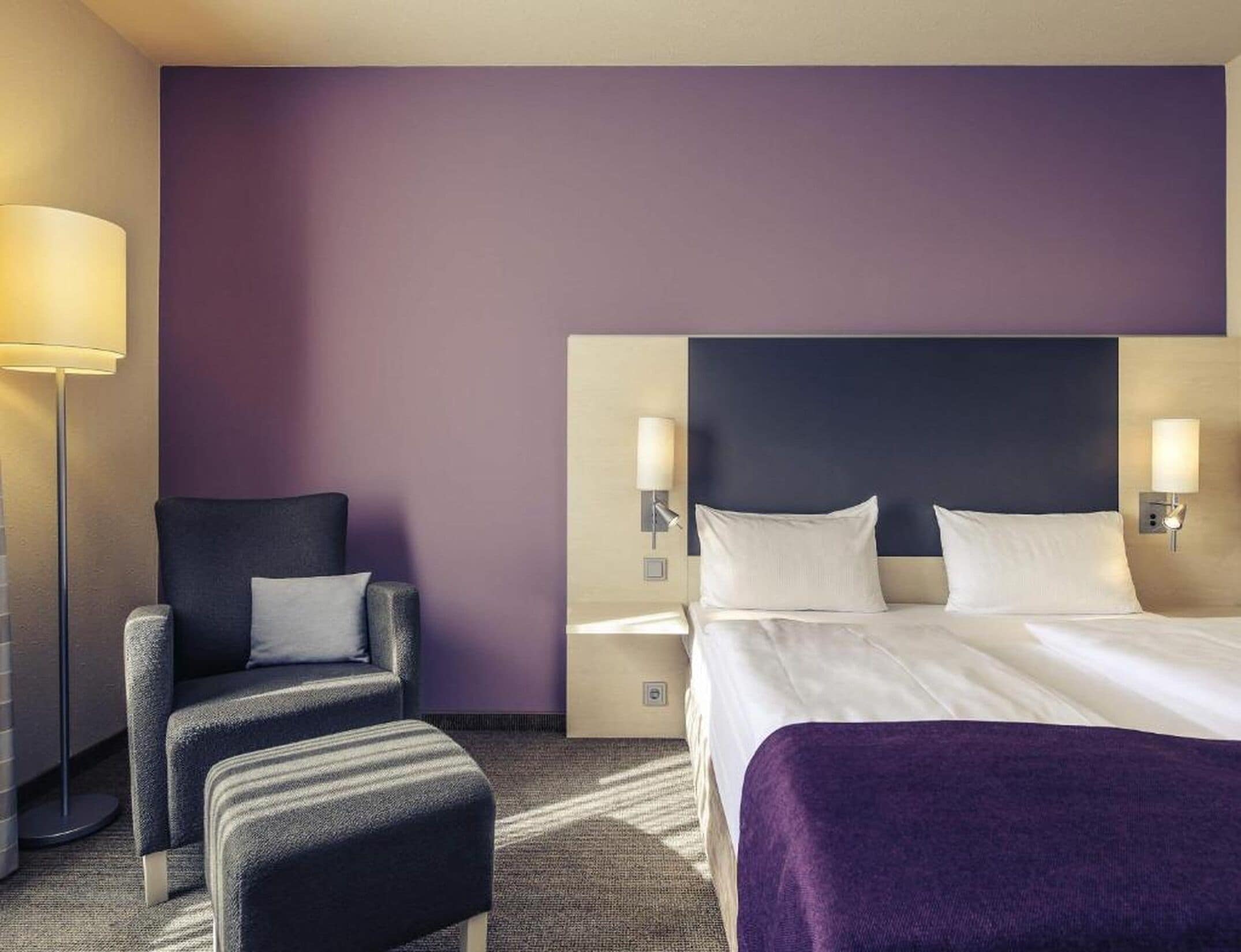 Ein Hotelzimmer mit Bett, Stuhl, Nachttisch und Lampe.