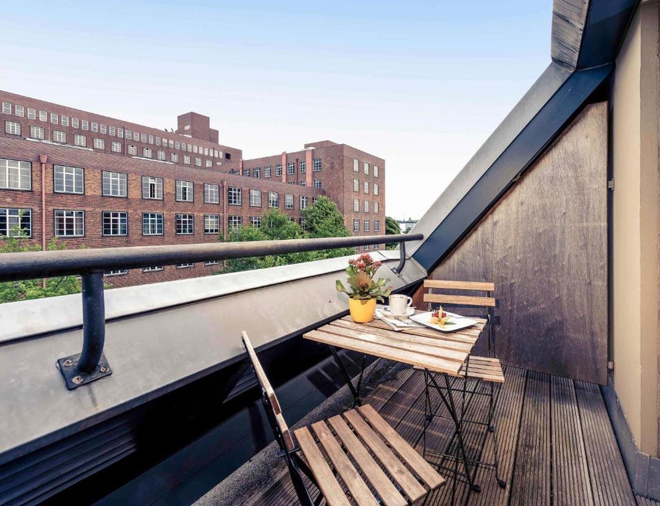 A balcony with a table, chairs, and a potted plant.