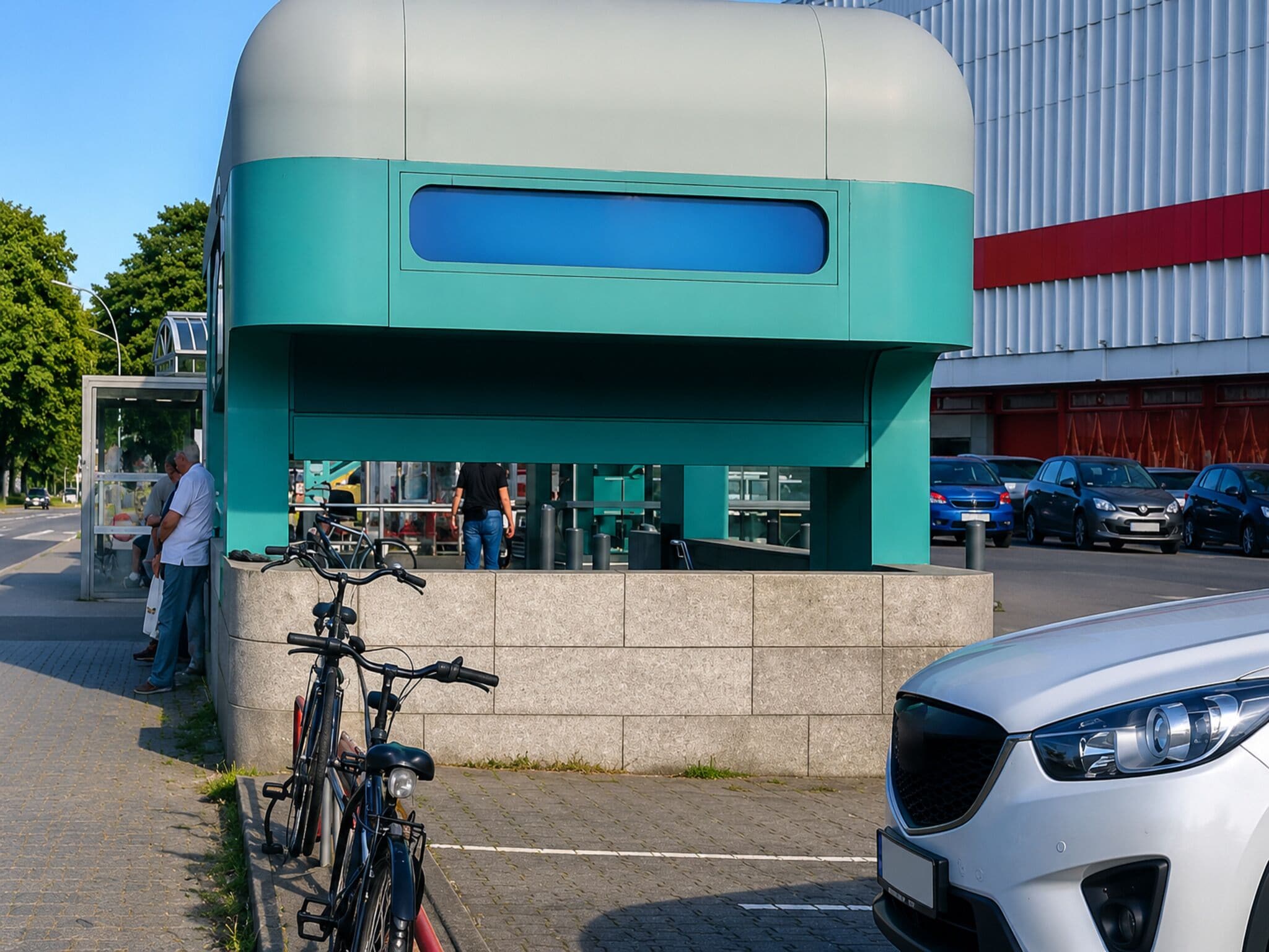 Un edificio moderno con una fachada destacada en verde y blanco, una bicicleta estacionada adelante y un coche blanco cerca.