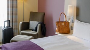 A hotel room with a bed, a chair, a suitcase, a handbag, and a lamp. - Sunday Hotel Berlin City West (Berlin)