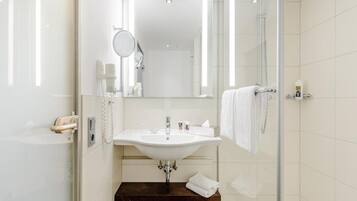 A modern bathroom with a glass shower enclosure, a white sink, and a mirror above it.