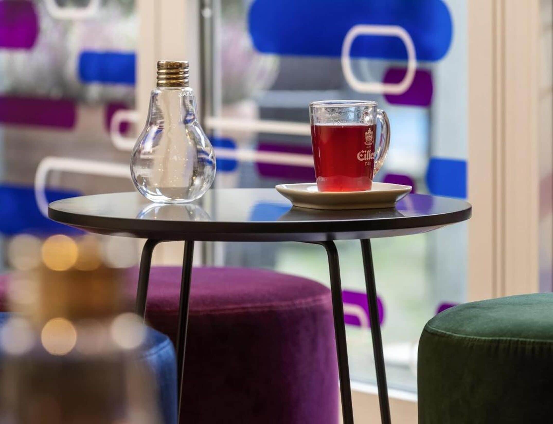 A table with a clear glass bottle and a glass of red tea.