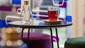 Ett bord med en genomskinlig glasflaska och ett glas rött te.