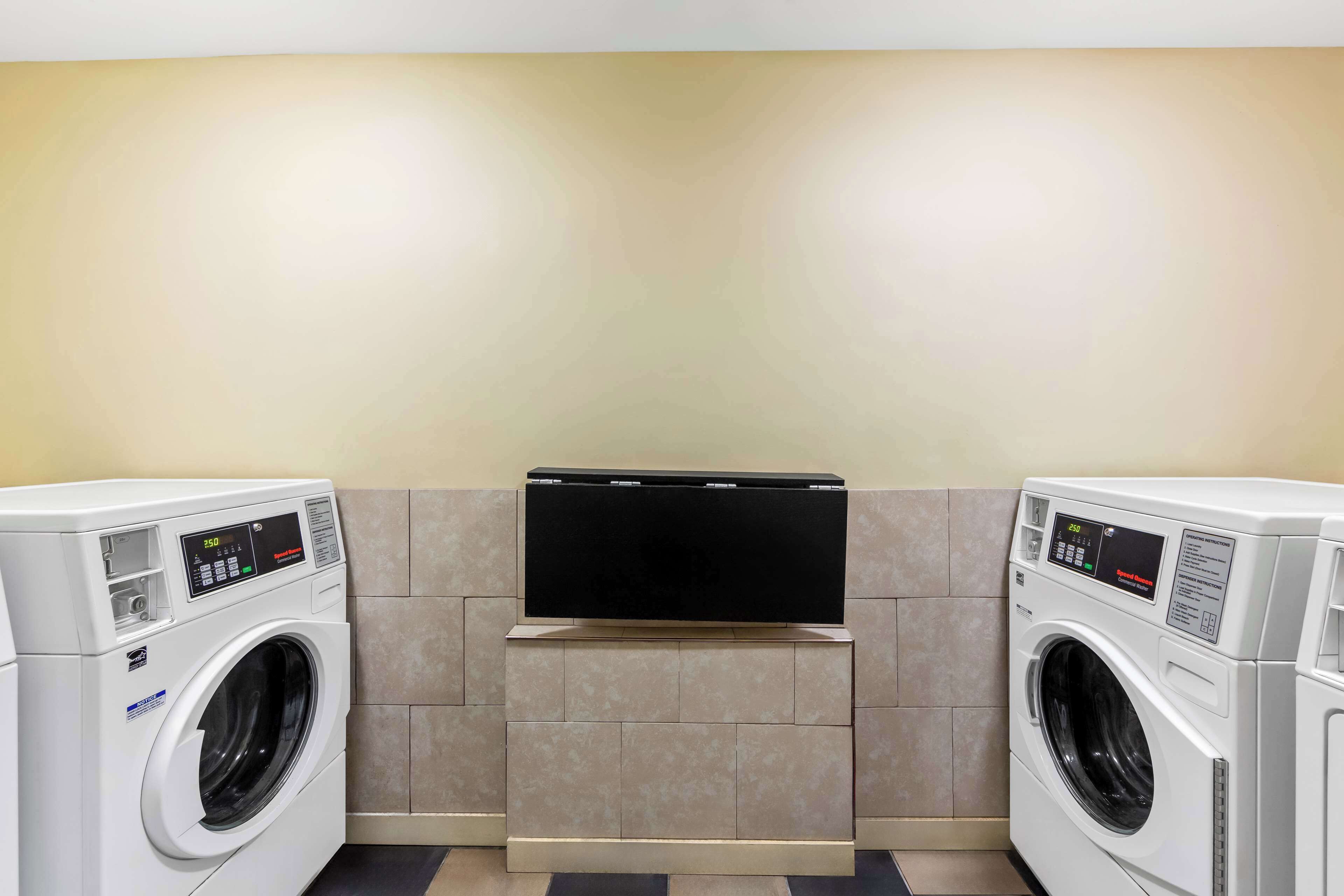 Een wasserette met twee voorladers en een flatscreen televisie aan de muur.