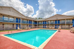 Un motel con piscina, varios balcones y un deck con tejas rojas.
