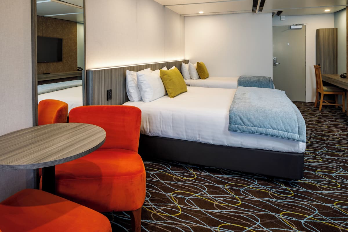 A hotel room with two beds, a TV, a desk, and a chair.