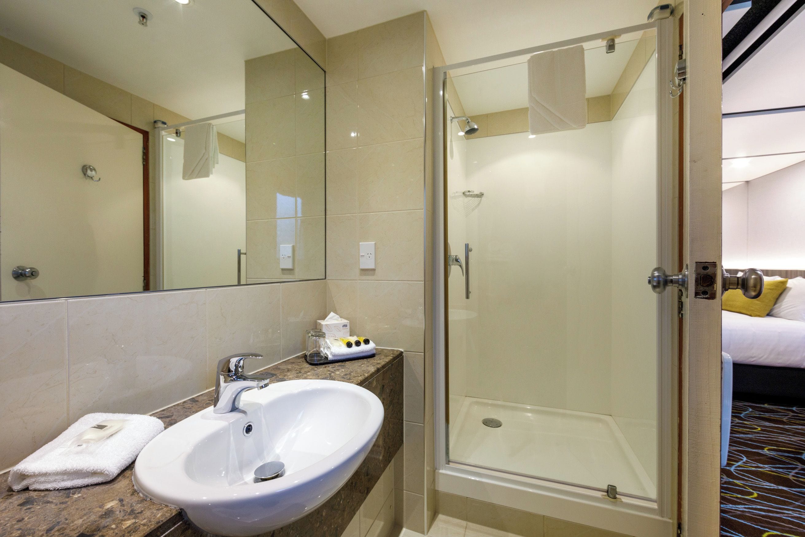 Un baño moderno con cabina de ducha de vidrio, un lavabo blanco y encimera de mármol.