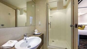 Un baño moderno con cabina de ducha de vidrio, un lavabo blanco y encimera de mármol.