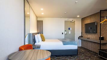 A hotel room with a bed, a round table, a TV, and a mirror.