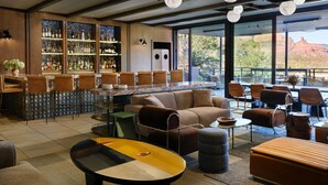 A bar area with a bar counter, seating, and a view of the outdoors. - Sky Rock Sedona, a Tribute Portfolio Hotel (Sedona)