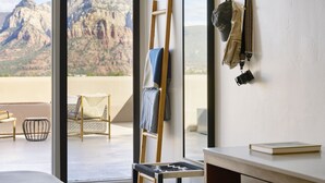 A room with a large window overlooking a mountainous landscape, a wooden ladder, a chair, and a hanging bag. - Sky Rock Sedona, a Tribute Portfolio Hotel (Sedona)