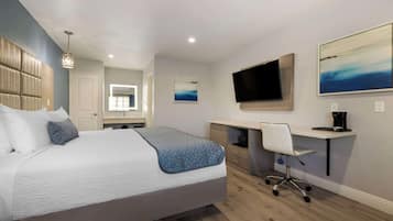 A modern bedroom with a large bed, a desk, a chair, a TV, and artwork on the walls.