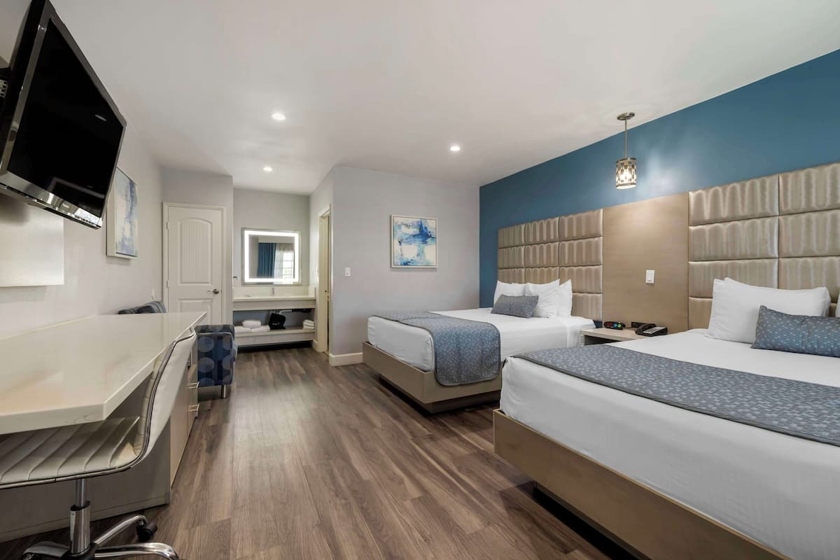 Une chambre d’hôtel avec deux lits, un bureau, une télévision et une salle de bain.